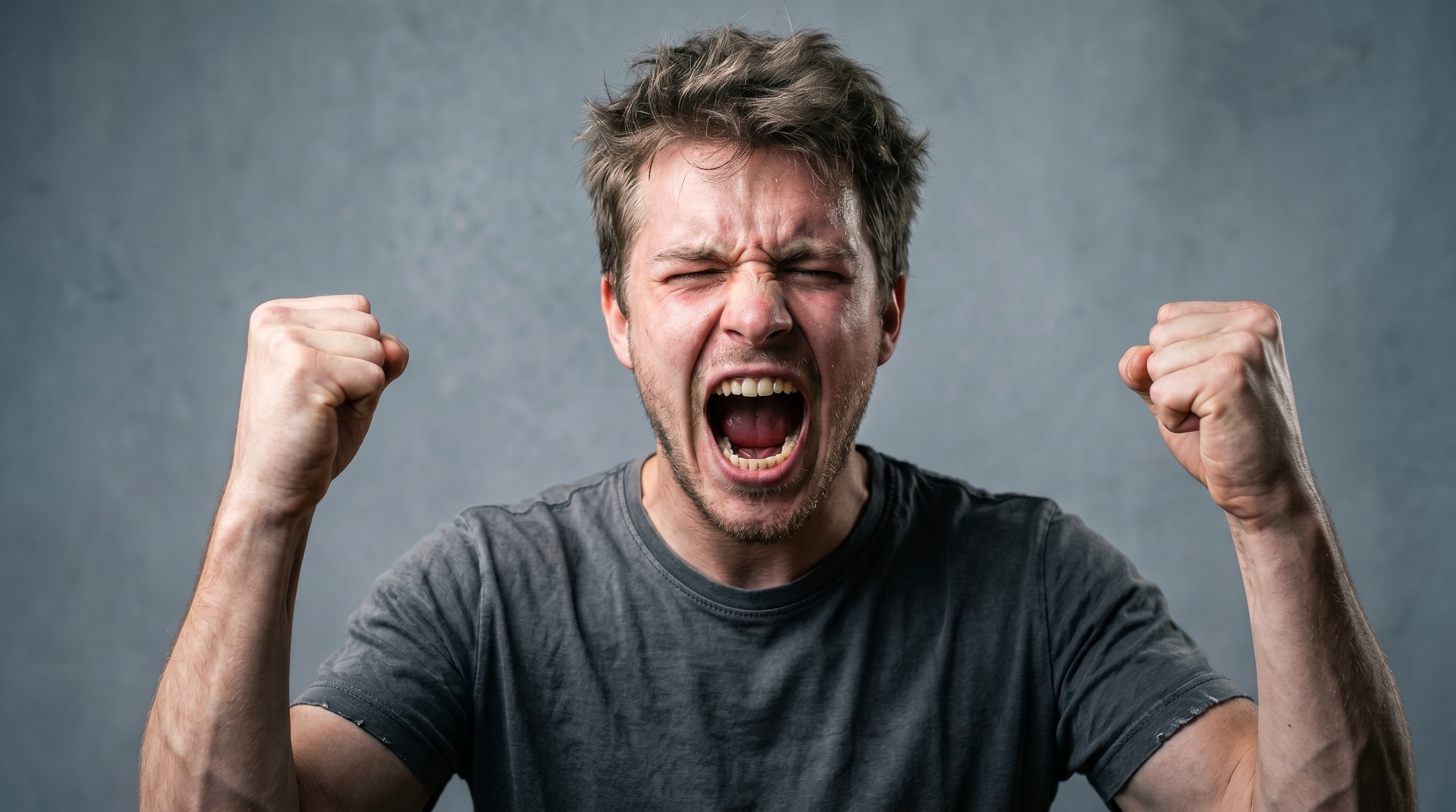 Hombre joven gritando con los puños cerrados, mostrando enojo intenso y frustración